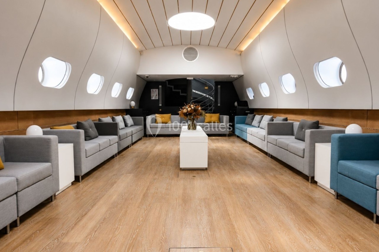 Intérieur spacieux et lumineux d'un salon avec canapés modernes, table basse et fenêtres arrondies.
