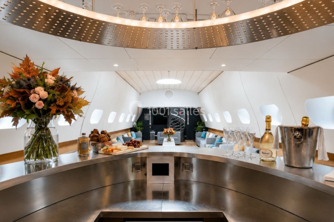 Intérieur luxueux d'un avion aménagé avec un bar circulaire, des fleurs, des boissons et des sièges confortables en arrière…