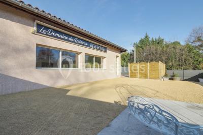 Salle lumineuse avec tables décorées de nappes blanches et chemins de table verts, prête pour un événement.