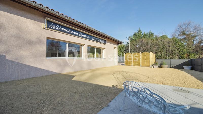 Façade d'un bâtiment avec une enseigne ’Le Domaine du Roucas’, entouré d'une cour en gravier et de végétation.