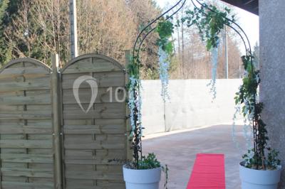 Salle lumineuse avec tables décorées de nappes blanches et chemins de table verts, prête pour un événement.