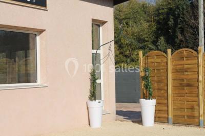 Salle lumineuse avec tables décorées de nappes blanches et chemins de table verts, prête pour un événement.