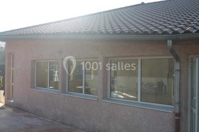 Salle lumineuse avec tables décorées de nappes blanches et chemins de table verts, prête pour un événement.