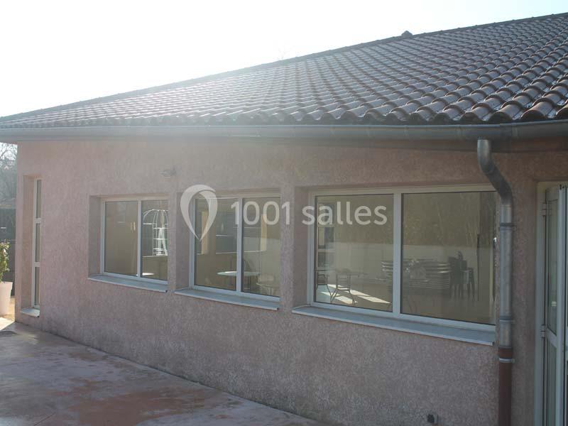 Façade d'un bâtiment avec des fenêtres vitrées et un toit en tuiles, éclairée par une lumière naturelle.