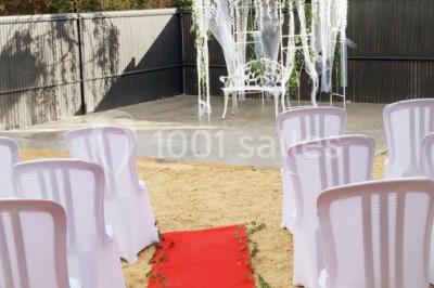 Salle lumineuse avec tables décorées de nappes blanches et chemins de table verts, prête pour un événement.