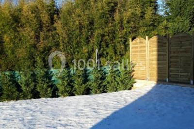 Salle lumineuse avec tables décorées de nappes blanches et chemins de table verts, prête pour un événement.