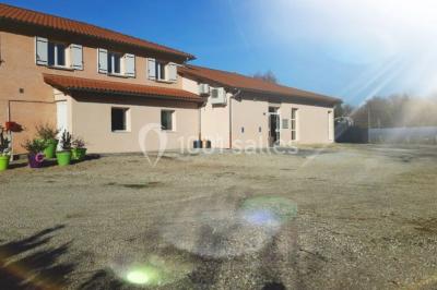 Salle lumineuse avec tables décorées de nappes blanches et chemins de table verts, prête pour un événement.