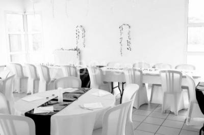Salle lumineuse avec tables décorées de nappes blanches et chemins de table verts, prête pour un événement.