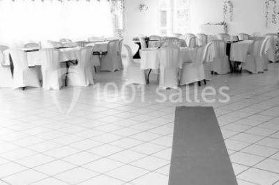 Salle lumineuse avec tables décorées de nappes blanches et chemins de table verts, prête pour un événement.