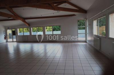 Salle lumineuse avec tables décorées de nappes blanches et chemins de table verts, prête pour un événement.