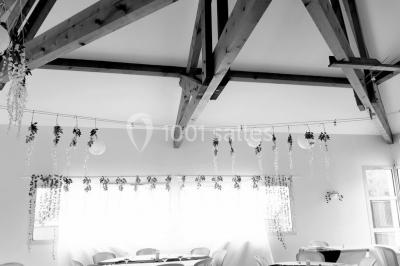 Salle lumineuse avec tables décorées de nappes blanches et chemins de table verts, prête pour un événement.