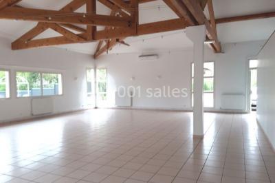 Salle lumineuse avec tables décorées de nappes blanches et chemins de table verts, prête pour un événement.