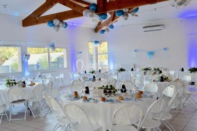 Salle lumineuse avec tables décorées de nappes blanches et chemins de table verts, prête pour un événement.
