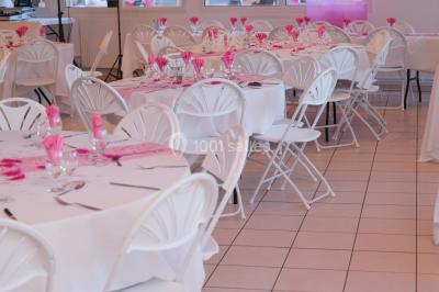Salle lumineuse avec tables décorées de nappes blanches et chemins de table verts, prête pour un événement.