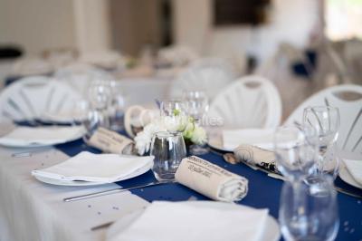 Salle lumineuse avec tables décorées de nappes blanches et chemins de table verts, prête pour un événement.