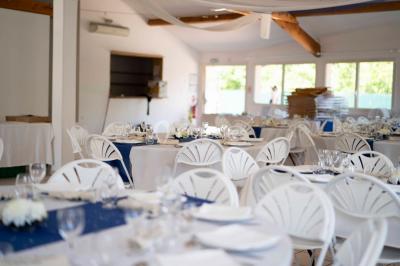 Salle lumineuse avec tables décorées de nappes blanches et chemins de table verts, prête pour un événement.