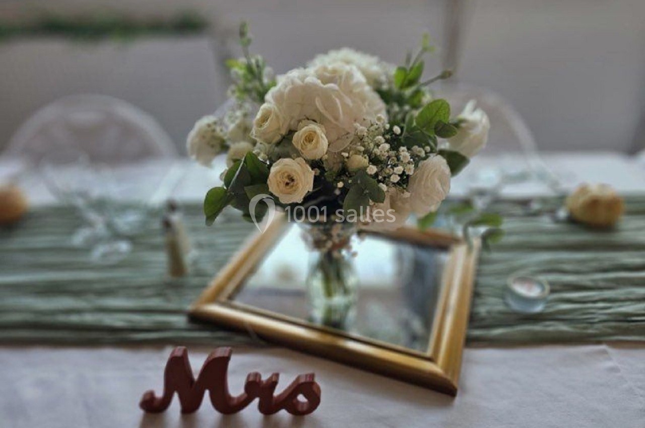 Bouquet de fleurs blanches sur une table décorée avec un miroir doré et une inscription ’Mrs’ en bois.