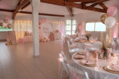 Arche de mariage décorée de fleurs blanches et vertes, avec deux chaises pliantes blanches devant, en extérieur ensoleillé.