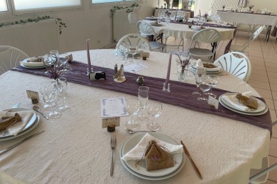 Arche de mariage décorée de fleurs blanches et vertes, avec deux chaises pliantes blanches devant, en extérieur ensoleillé.