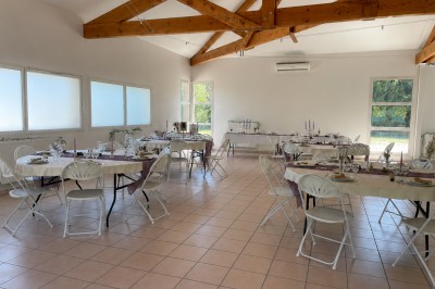 Arche de mariage décorée de fleurs blanches et vertes, avec deux chaises pliantes blanches devant, en extérieur ensoleillé.