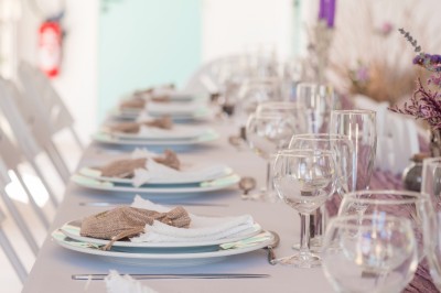Arche de mariage décorée de fleurs blanches et vertes, avec deux chaises pliantes blanches devant, en extérieur ensoleillé.