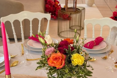 Arche de mariage décorée de fleurs blanches et vertes, avec deux chaises pliantes blanches devant, en extérieur ensoleillé.