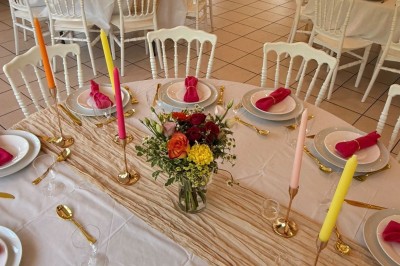Arche de mariage décorée de fleurs blanches et vertes, avec deux chaises pliantes blanches devant, en extérieur ensoleillé.