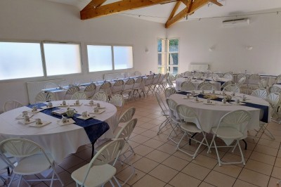 Arche de mariage décorée de fleurs blanches et vertes, avec deux chaises pliantes blanches devant, en extérieur ensoleillé.
