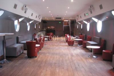 Personnes dansant dans une salle faiblement éclairée avec des lumières colorées créant une ambiance festive.