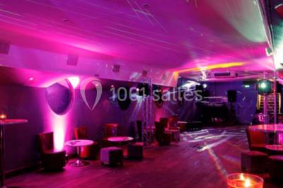 Personnes dansant dans une salle faiblement éclairée avec des lumières colorées créant une ambiance festive.