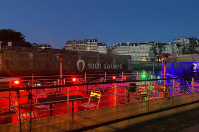 Personnes dansant dans une salle faiblement éclairée avec des lumières colorées créant une ambiance festive.