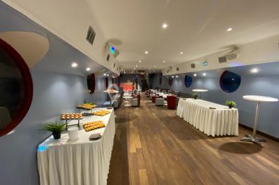 Personnes dansant dans une salle faiblement éclairée avec des lumières colorées créant une ambiance festive.