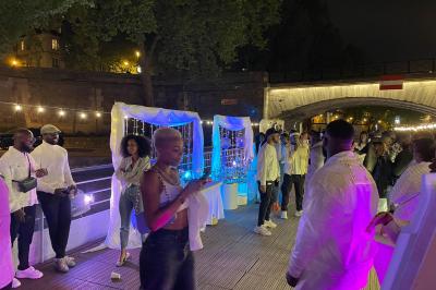 Personnes dansant dans une salle faiblement éclairée avec des lumières colorées créant une ambiance festive.