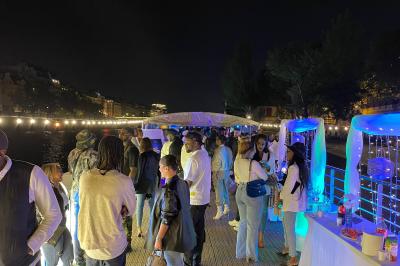 Personnes dansant dans une salle faiblement éclairée avec des lumières colorées créant une ambiance festive.