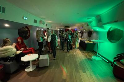 Personnes dansant dans une salle faiblement éclairée avec des lumières colorées créant une ambiance festive.