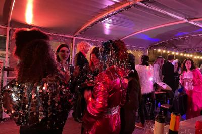 Personnes dansant dans une salle faiblement éclairée avec des lumières colorées créant une ambiance festive.