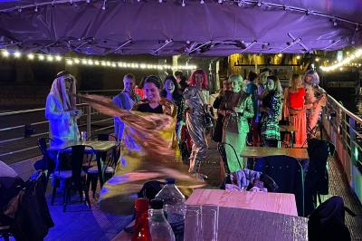 Personnes dansant dans une salle faiblement éclairée avec des lumières colorées créant une ambiance festive.