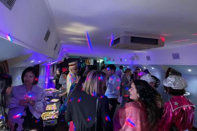 Personnes dansant dans une salle faiblement éclairée avec des lumières colorées créant une ambiance festive.