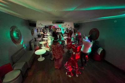 Personnes dansant dans une salle faiblement éclairée avec des lumières colorées créant une ambiance festive.