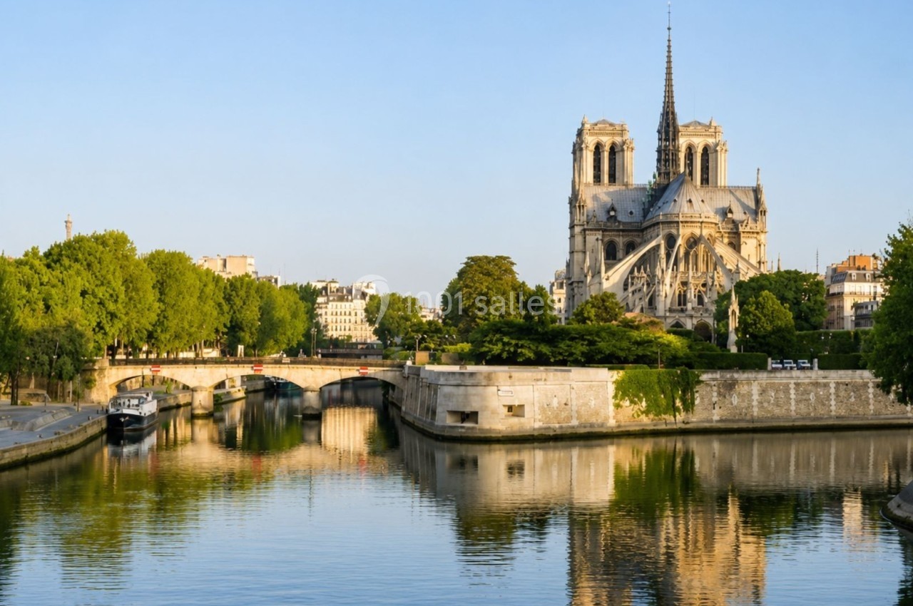 Vue de la cathédrale Notre-Dame de Paris depuis la Seine, entourée d'arbres et reflétée dans l'eau calme.