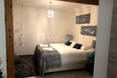 Chambre avec lit double, fauteuil, lampadaire et porte en bois, décorée dans un style sobre et lumineux.