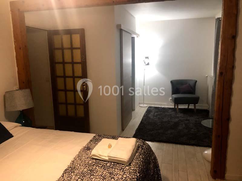 Chambre avec lit double, fauteuil, lampadaire et porte en bois, décorée dans un style sobre et lumineux.