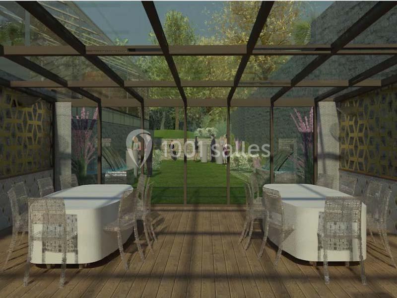 Salle vitrée avec tables et chaises, donnant sur un jardin où des personnes se tiennent debout.