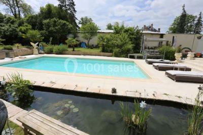 Chambre avec lit double, fauteuil, lampadaire et porte en bois, décorée dans un style sobre et lumineux.