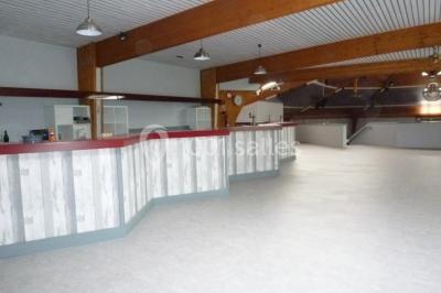 Bar avec éclairage rouge, comptoir en bois, étagères avec verres et décorations, ambiance tamisée.