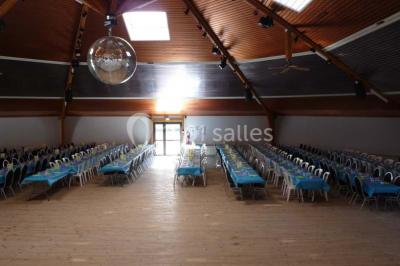 Bar avec éclairage rouge, comptoir en bois, étagères avec verres et décorations, ambiance tamisée.