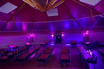 Bar avec éclairage rouge, comptoir en bois, étagères avec verres et décorations, ambiance tamisée.