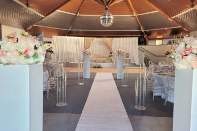 Bar avec éclairage rouge, comptoir en bois, étagères avec verres et décorations, ambiance tamisée.