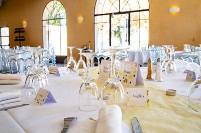 Chambre lumineuse avec murs orange, lit double, sol en terre cuite, table près d'une fenêtre et cloison en bois.