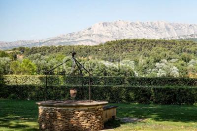 Chambre lumineuse avec murs orange, lit double, sol en terre cuite, table près d'une fenêtre et cloison en bois.